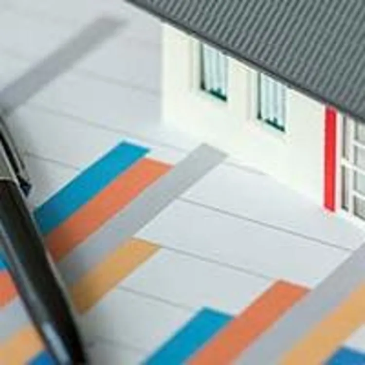 small model home and calculator sitting on bar charts