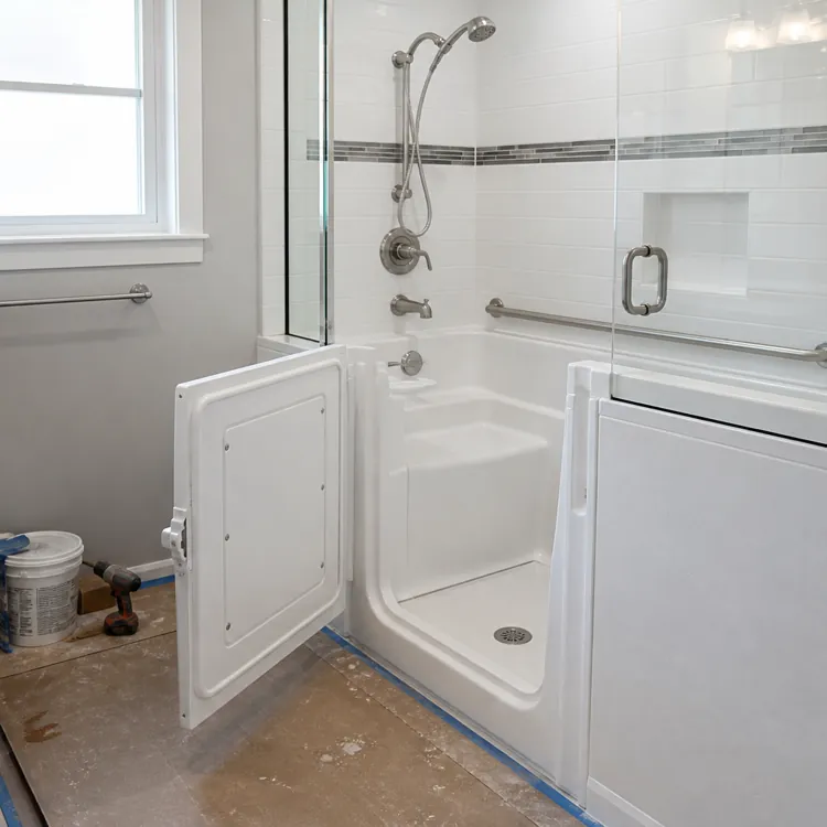 Walk-in bathtub with open door, grab bars, and handheld shower in a bathroom under renovation