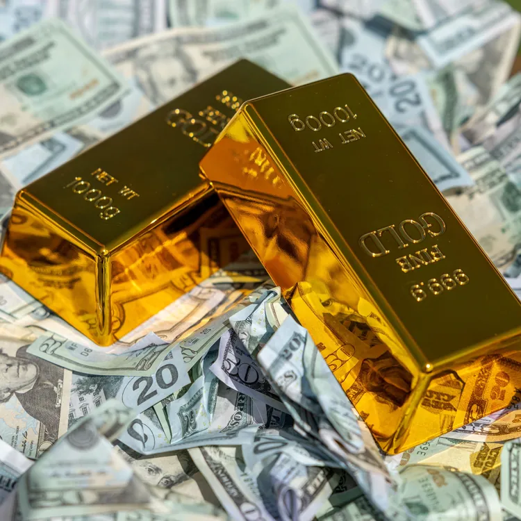 Two gold bars placed on top of scattered US dollar bills