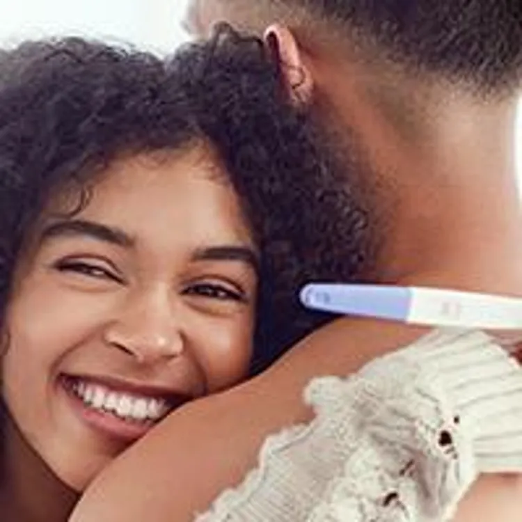 couple hugging holding pregnancy test