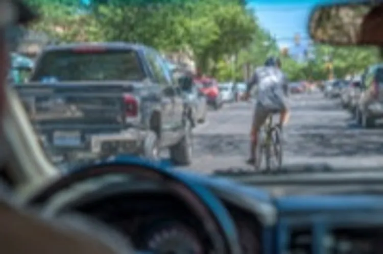 the interior of a vehicle with a view of a cyclist in the middle of the street
