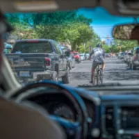 the interior of a vehicle with a view of a cyclist in the middle of the street