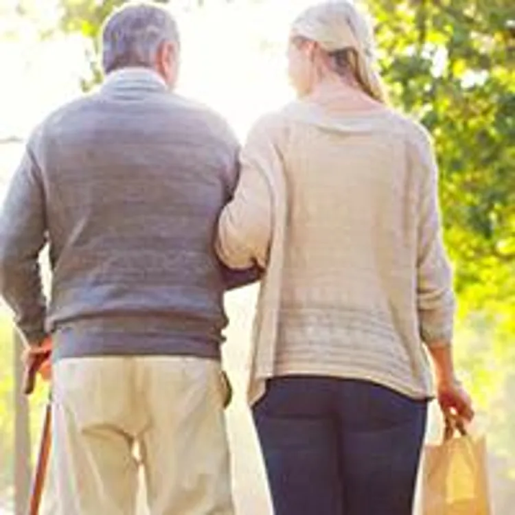 daughter walking with elderly father in park