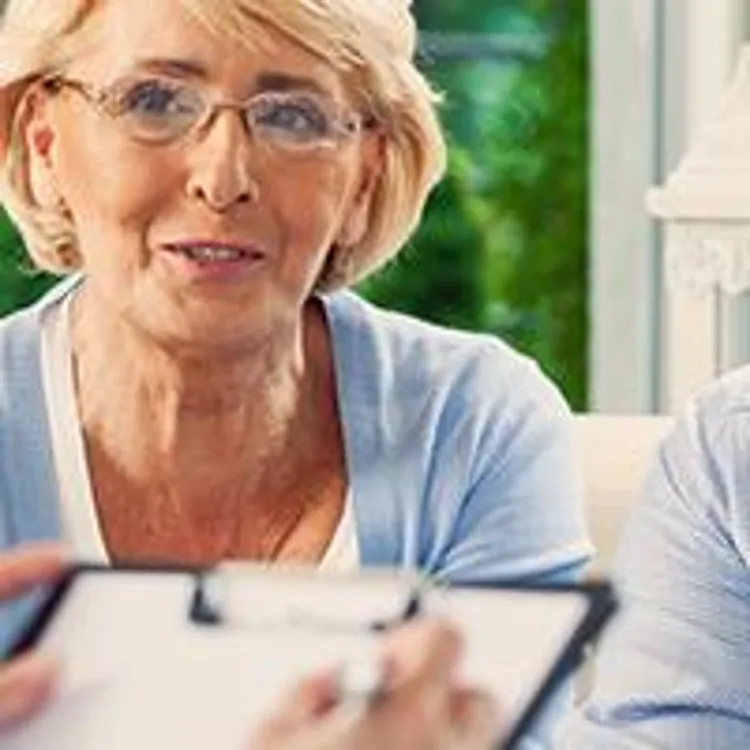older couple visiting with saleswoman holding a clipboard