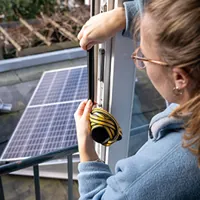woman sticking draft strips with solar panels on background