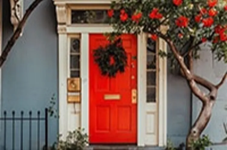 entry porch of a house with a red door with wreath