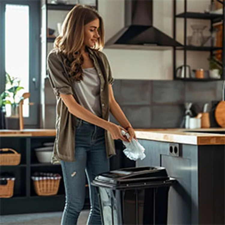 woman placing garbage into a trash compactor in the kitchen
