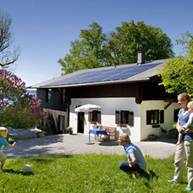 a family spending time in the yard and a house topped with solar panels in the background