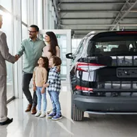 family with young children meeting salesperson in car showroom