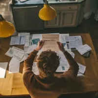 a person sitting at a desk littered with bills