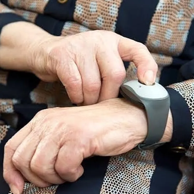 Elderly person pressing a button on a medical alert wrist device