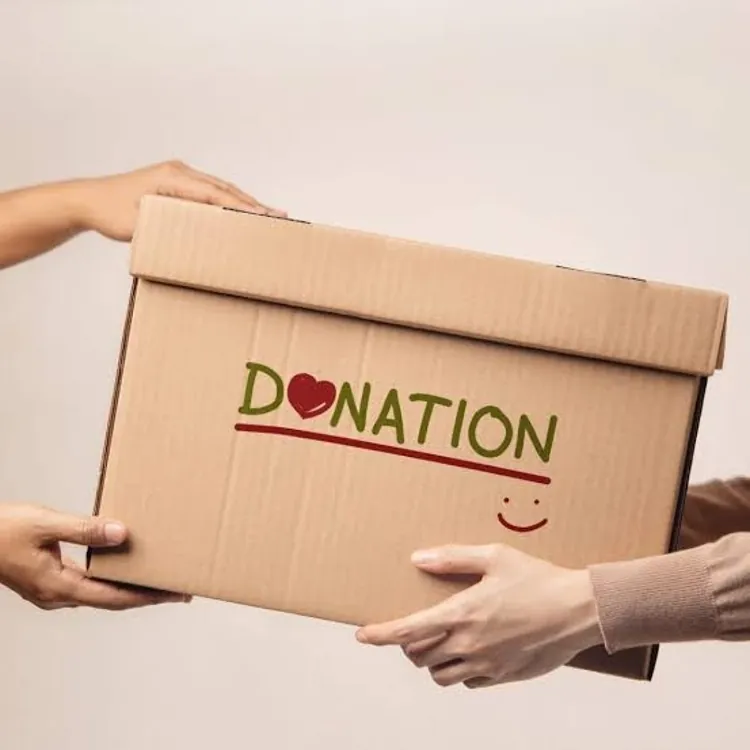 Two hands exchanging a cardboard box labeled donation with a heart and smiley face.