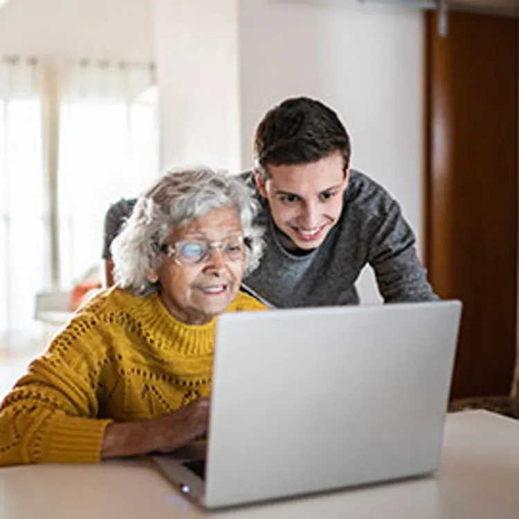 grandson and grandmother using a laptop at home