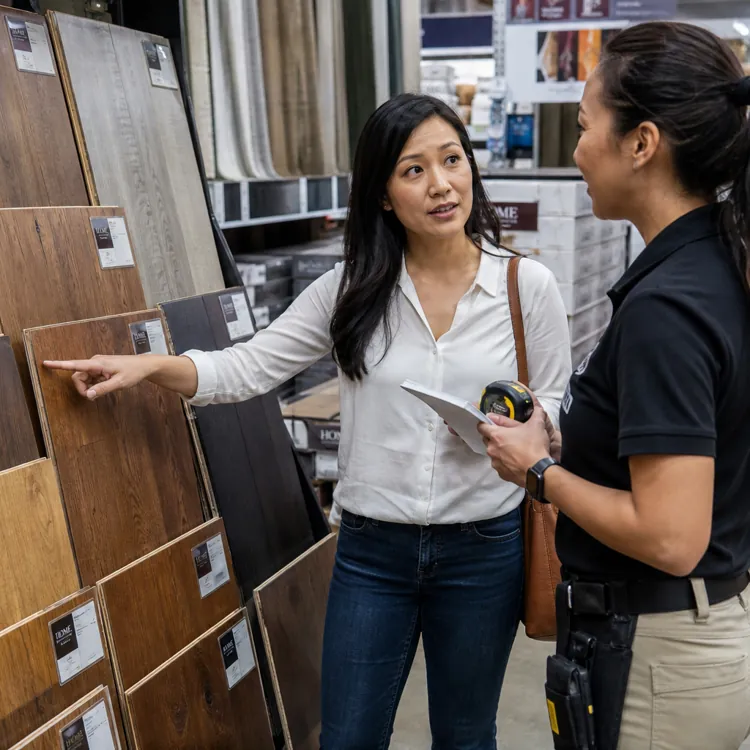 Woman discussing wood flooring options with a store employee in a flooring showroom