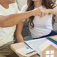 happy couple fist-bumping after making calculations on a home loan