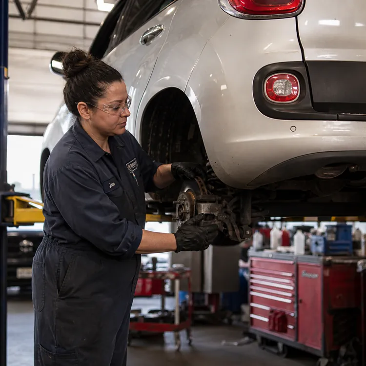 Mechanic working on a lifted white car in a garage