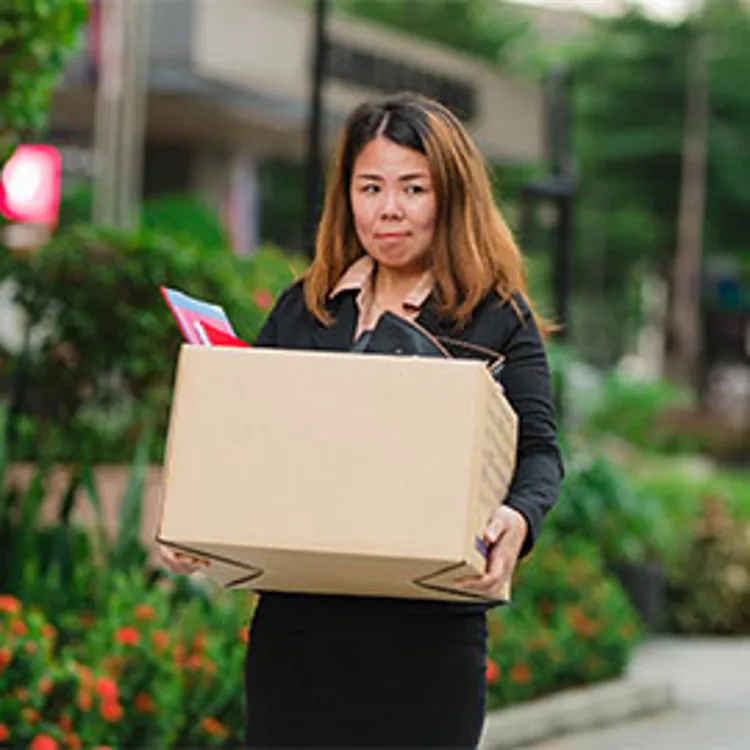 lady carrying box full of personal things leaving office