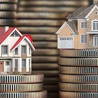 miniature houses of different sizes with different values placed on top of stacks of coins