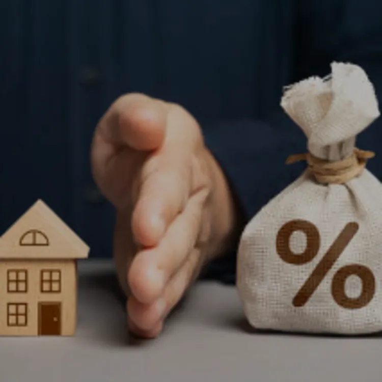 Hand separating small house model and money bag with percent symbol