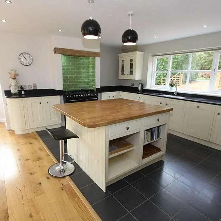 Spacious kitchen with a central island, white cabinets, large windows, and a dining table in the corner