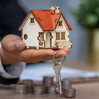 man holding miniature house with keys
