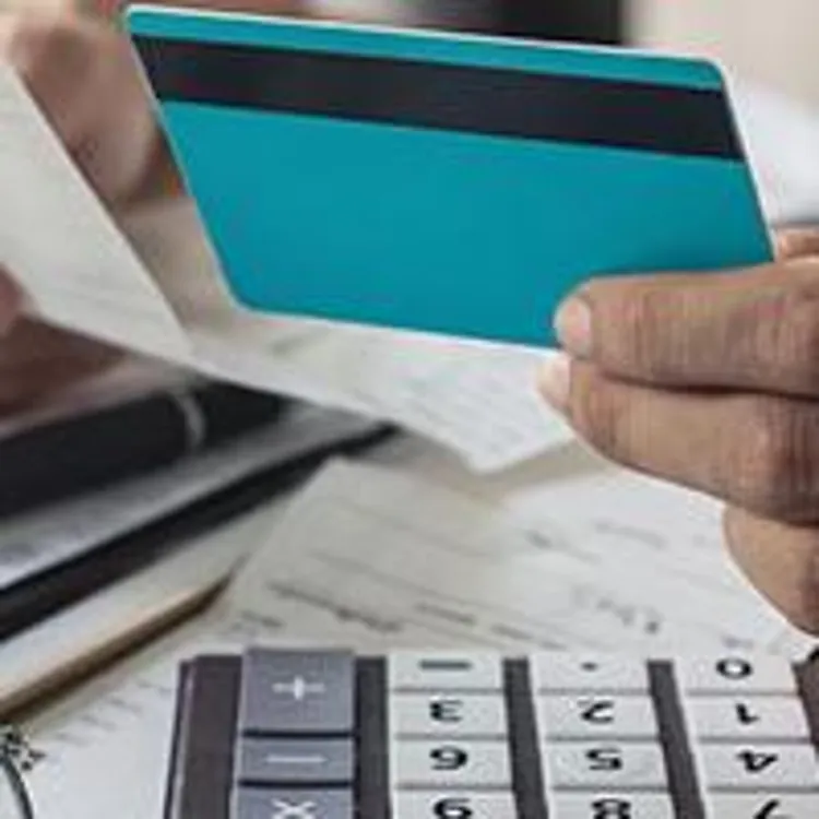 Hands holding credit card and billing statements