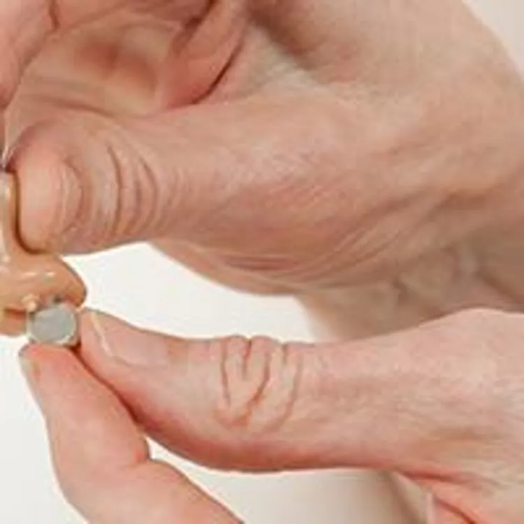 older woman replacing hearing aid batteries