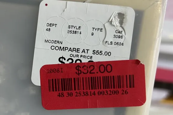 Close-up of a retail price tag showing a red $32.00 sticker over a white label