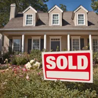 a beautiful home with a red sold sign on the front yard