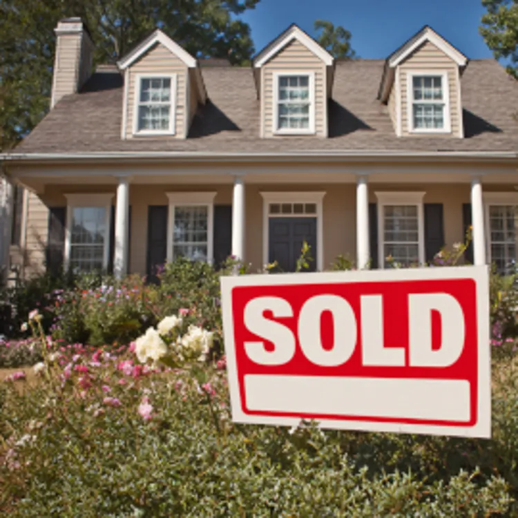a beautiful home with a red sold sign on the front yard