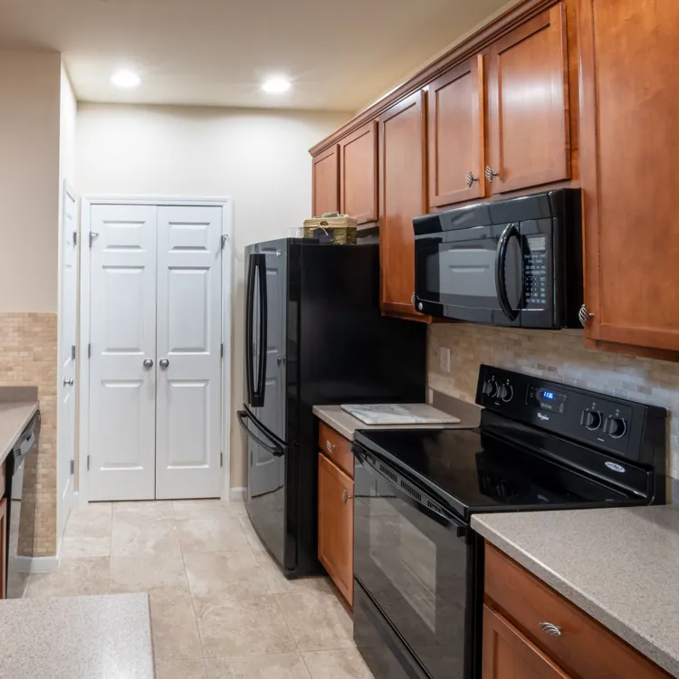 Modern kitchen with wood cabinets, black appliances, double sink, and tile backsplash