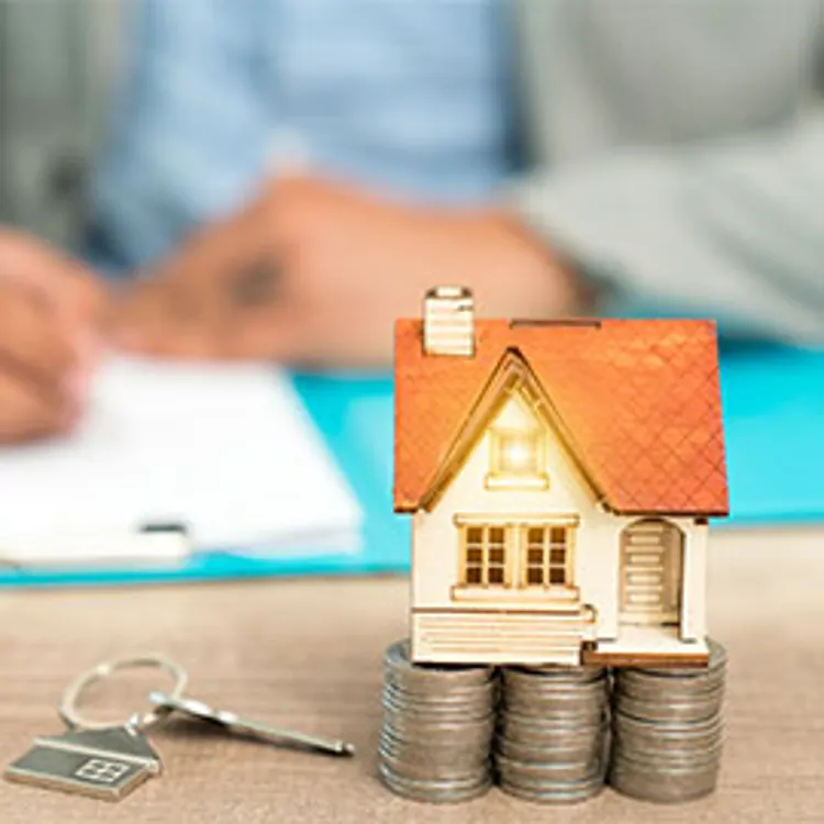 model house set set on top of coins with man signing home warranty contract in background