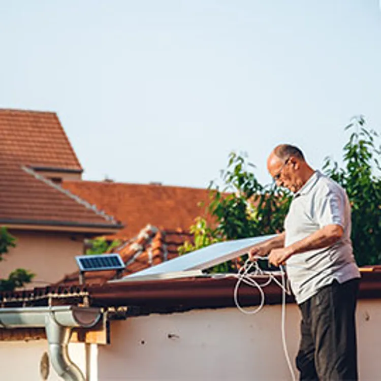 elderly man installing solar panel