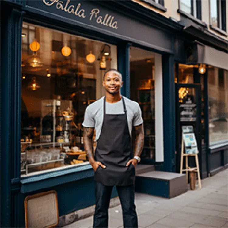 man wearing apron standing in front of stores