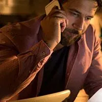 close up of a man talking on the phone while looking at a piece of paper