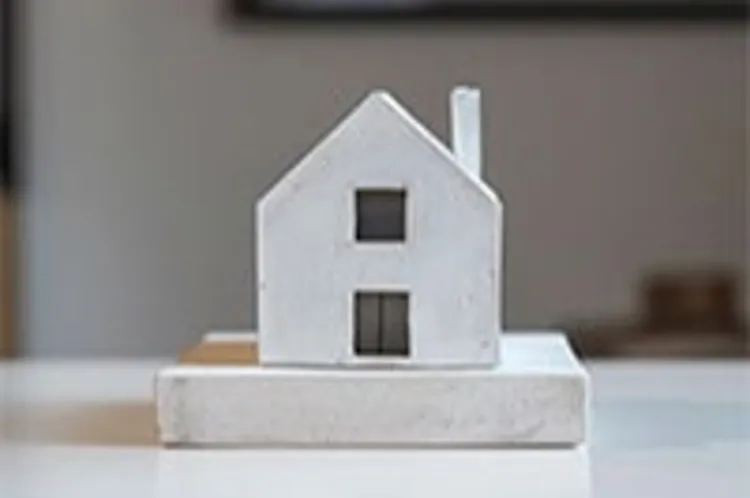 wooden model house with chimney and two windows on a table