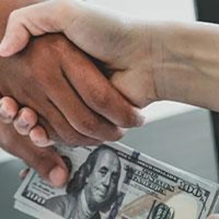 Man handing money to woman and shaking hands
