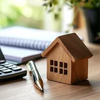 wooden model house paper notebook and calculator on a table