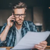 a man on the phone while looking at a document