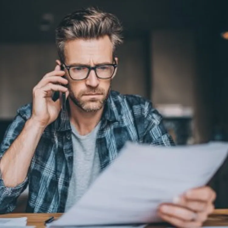 a man on the phone while looking at a document