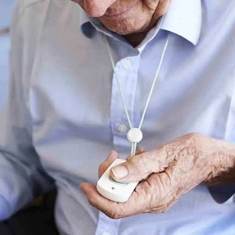 Senior person wearing a blue shirt holding a medical alert pendant on a lanyard
