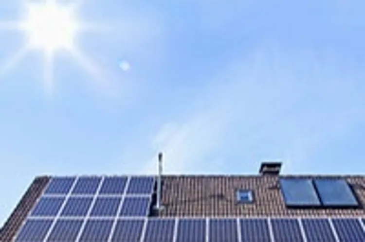 solar panels on houseroof in front of blue sky with sun