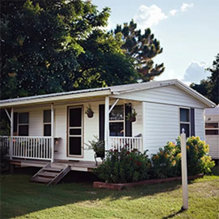 white mobile home with plants on the side