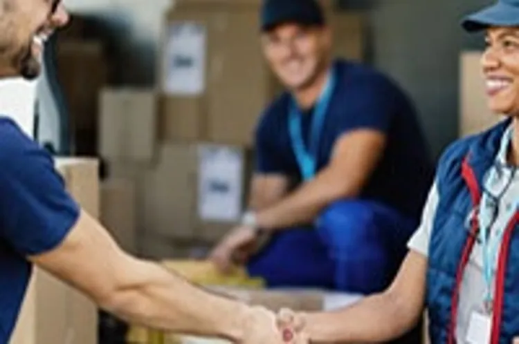 happy workers shaking hands and a male colleague in the background