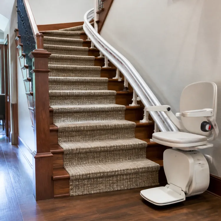 Stair lift installed along a carpeted staircase in a home near a living room area