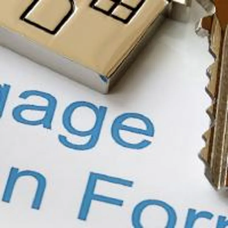 house key on top of mortgage loan application stamped with 'approved'