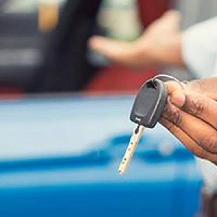 blue car and person holding keys
