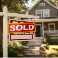 House with a sold sticker over a for sale sign in the front yard