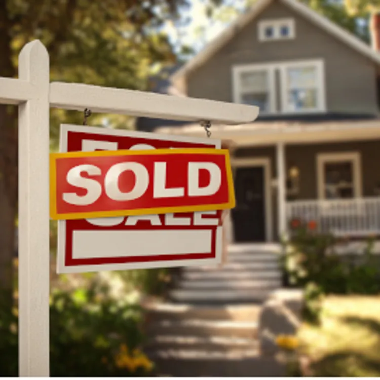 House with a sold sticker over a for sale sign in the front yard