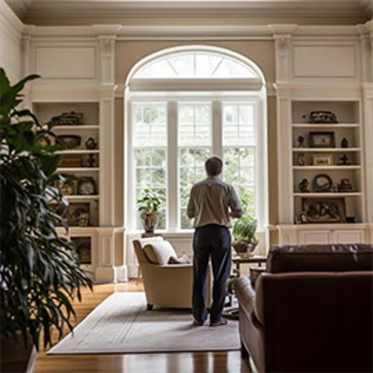 man standing in living room looking out home window